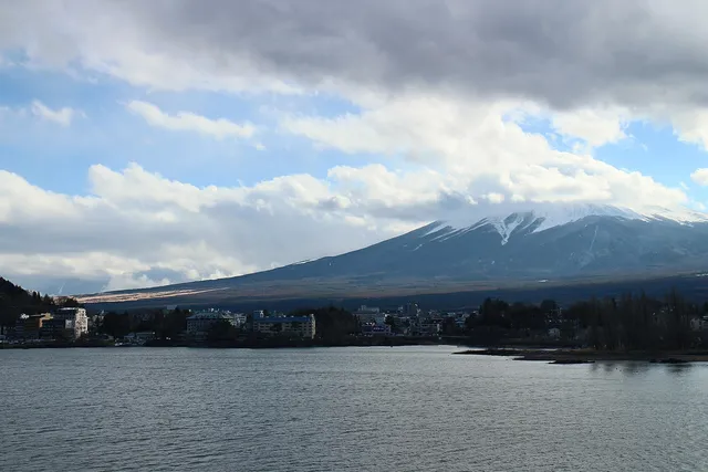 Mount Fuji rising behind a lake town, seen from a shinkansen-window vantage point on a clear day