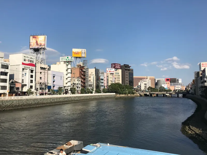 Yatai food stalls glowing along the Naka River at night in Fukuoka's Nakasu district