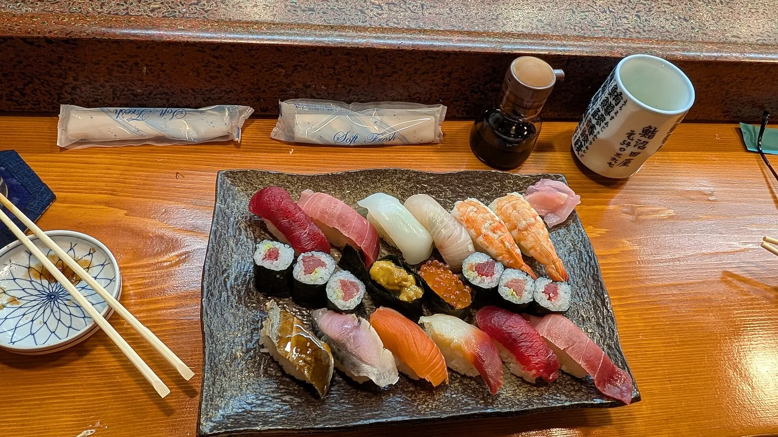 A platter of colorful nigiri sushi and maki rolls on a wooden counter