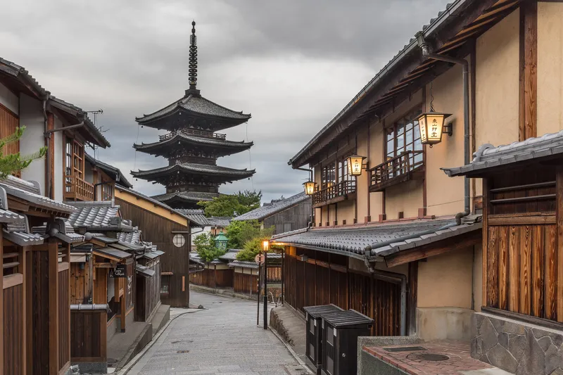 Historic Kyoto street with traditional machiya townhouses and a pagoda rising behind them
