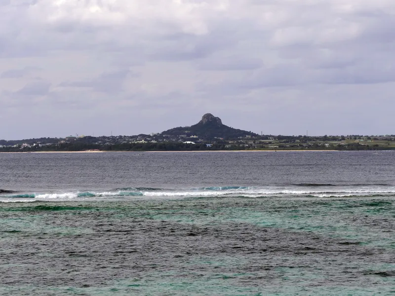 Turquoise water breaking on a white sand Okinawan beach under a wide sky