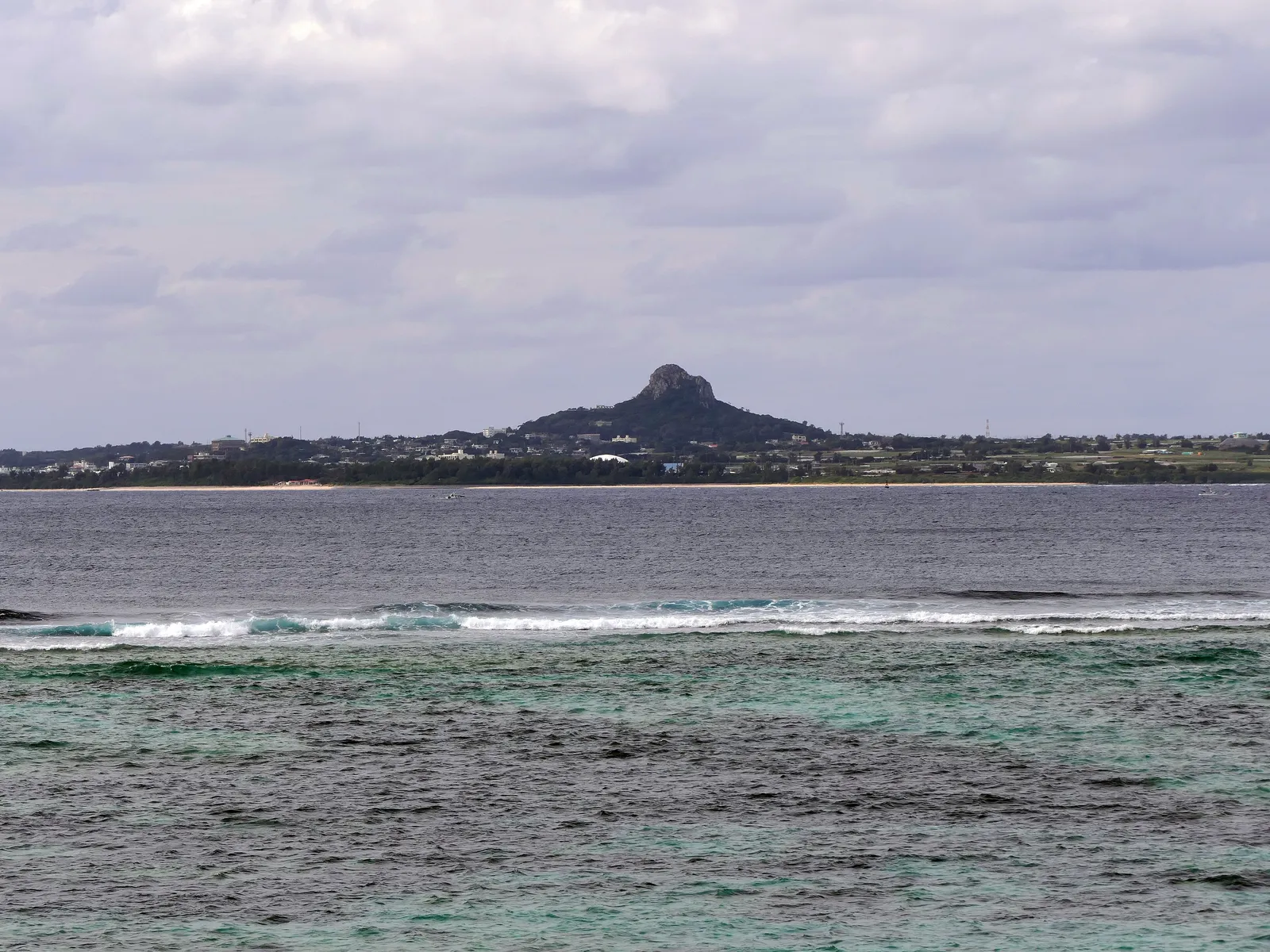 Turquoise water breaking on a white sand Okinawan beach under a wide sky