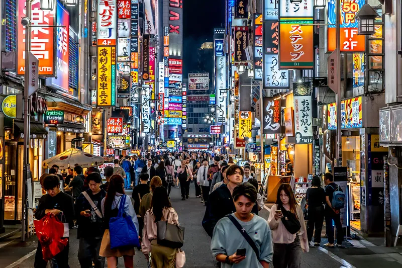 Tokyo skyline and Shibuya crossing glowing with neon signs at dusk